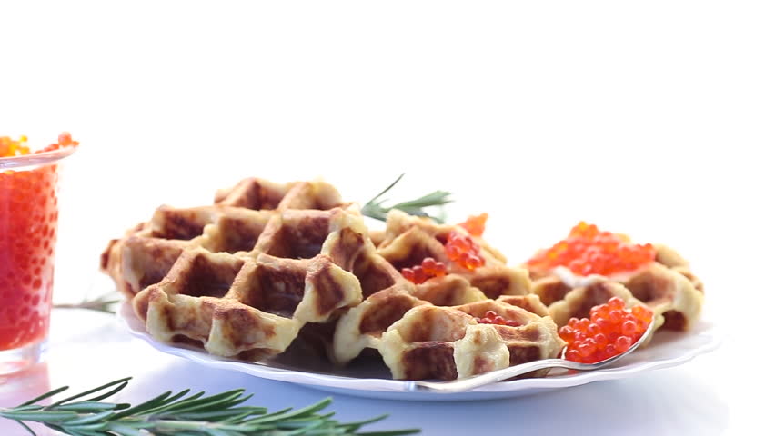 Potato waffles with red caviar on a white background.