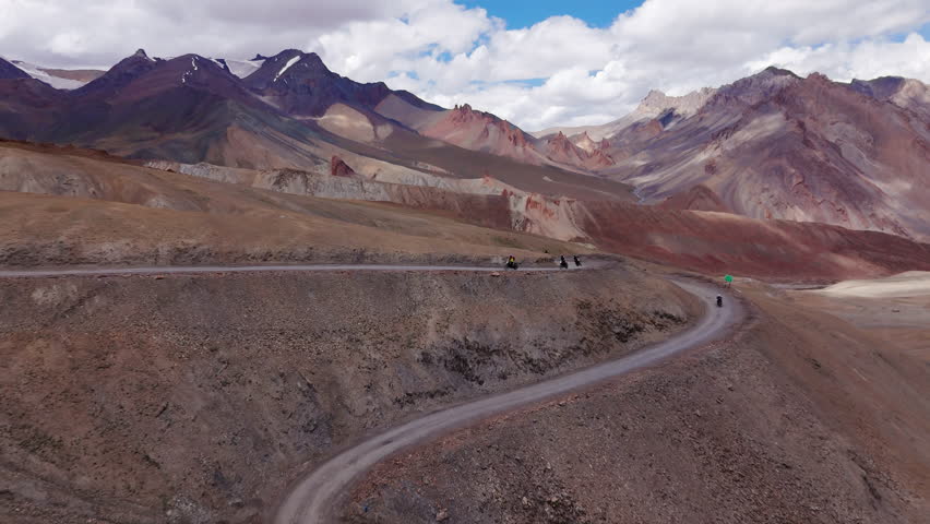 Motorcyclists riding on a winding mountain road, drone view