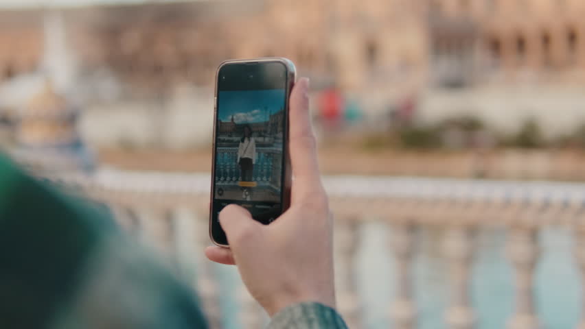 Close up of man's hand holding mobile phone, taking photo of girlfriend