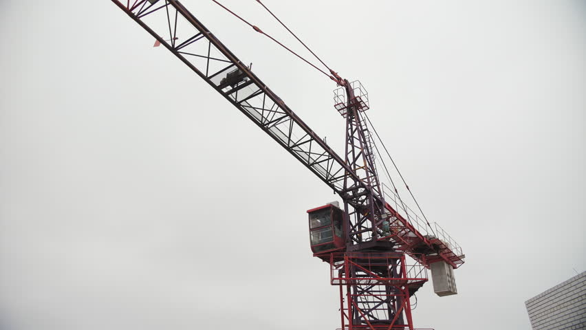 Large Red Construction Crane Against Cloudy Sky