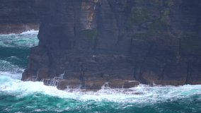 Powerful ocean waves crash against the base of the Cliffs of Moher, sending white spray into the air. The rugged coastline and towering cliffs showcase the untamed beauty of Ireland’s west coast. - Powered by Shutterstock - Get 15% off with code: PIKWIZARD15