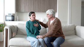 Mature woman suddenly feel heart distress, shortness of breath like asthma. Husband calming stroking, soothing wife on couch. Health scare, anxiety relief, overwhelming stress, deep concern of spouse - Powered by Shutterstock - Get 15% off with code: PIKWIZARD15