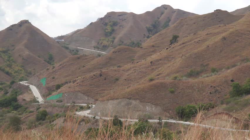 Aerial drone view of the road in Golomori island mountain peak with ocean on the background in Labuan Bajo, Indonesia.