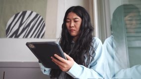 Business woman CEO decision concept. Woman with Long Black Hair Sitting Indoors, Holding Tablet in Light Blue Shirt, Surrounded by Modern Interior Design and Abstract Art Elements - Powered by Shutterstock - Get 15% off with code: PIKWIZARD15