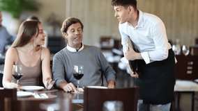 Young guy waiter taking order from couple adult man and young woman in restaurant - Powered by Shutterstock - Get 15% off with code: PIKWIZARD15