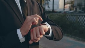 Businessman raises hand and looks at the smartwatch on it. Businessman is typing message on the smartwatch.  Modern gadgets and people concept. Modern communication. Close up, slow motion footage. - Powered by Shutterstock - Get 15% off with code: PIKWIZARD15