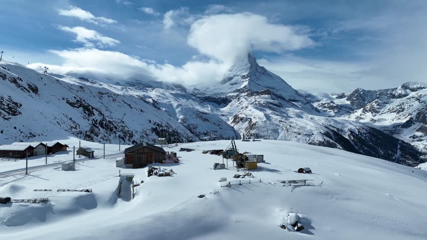Gornergrat bahn railway running towards summit station with Matterhorn mountain peak background in Zermatt on a sunny winter day. Swiss Alps, Switzerland travel journey trip. 4K Static Shot