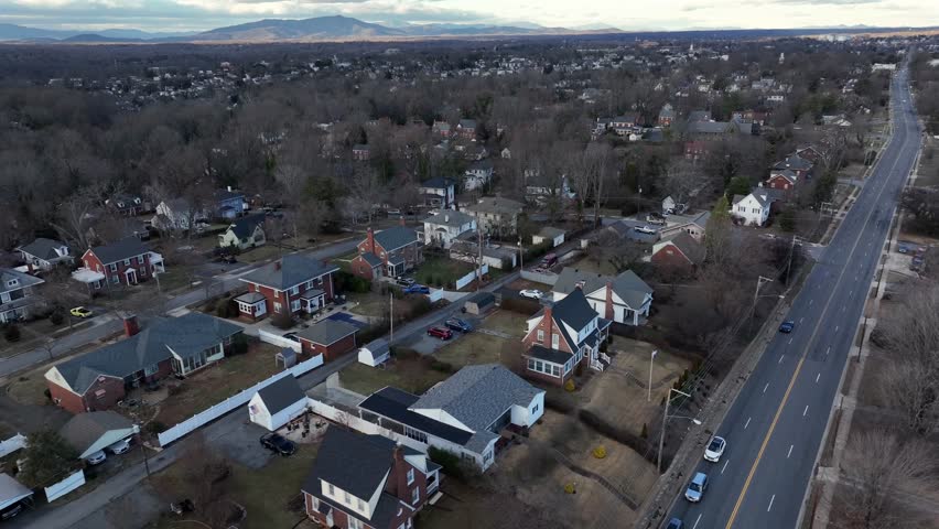 Victorian and colonial one family houses during cloudy day in America. Main intersection road with Leafless trees in Virginia. Aerial approaching wide shot.