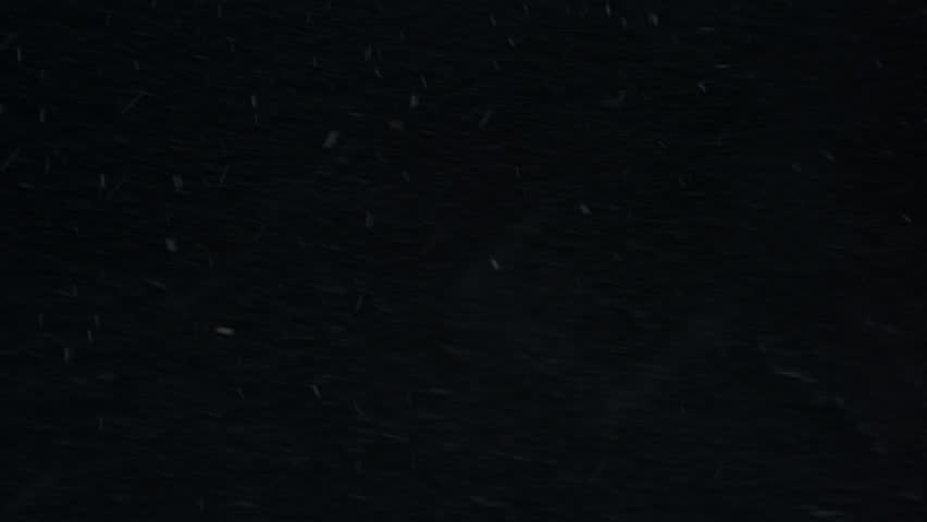 A powerful Icelandic storm covers a dark beach in snow and rain, with icy winds creating rough seas