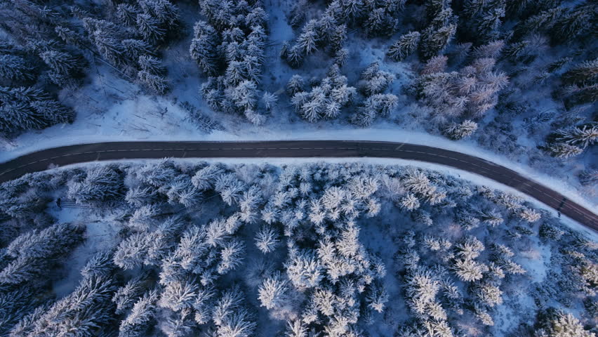 Stunning aerial shot showcasing a winding road through snowcovered forests in Courchevel, France, presenting a picturesque winter landscape