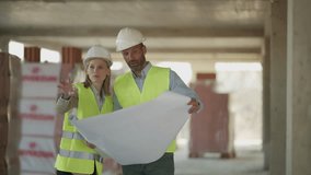Construction professionals wearing safety gear standing together, carefully reviewing architectural blueprints while analyzing project details on unfinished building site - Powered by Shutterstock - Get 15% off with code: PIKWIZARD15