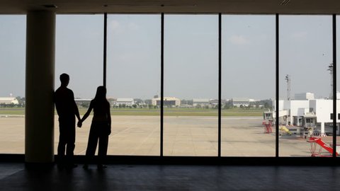silhouette of pair of lovers near the window in airport