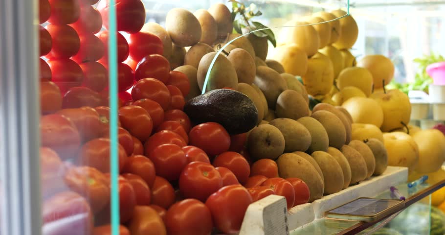 Colorful market display showcasing ripe tomatoes, golden sapodilla, and various yellow fruits representing seasonal produce abundance