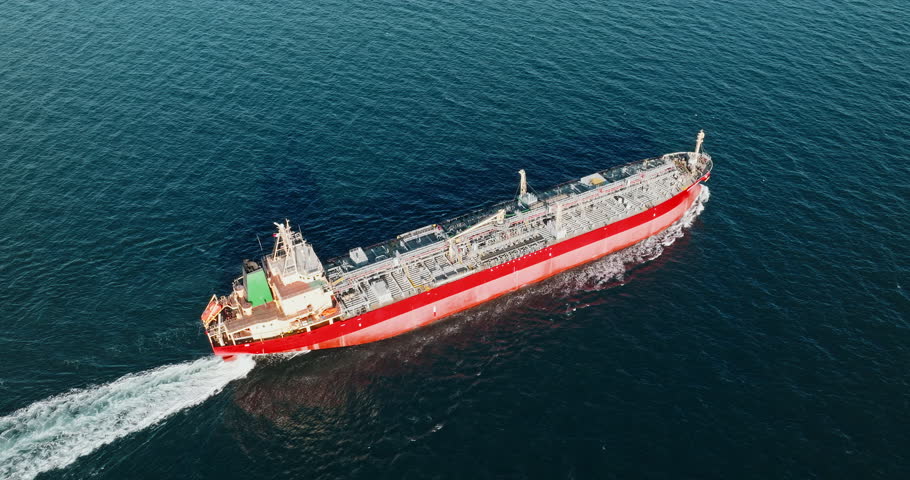 Red cargo tanker moves through Black Sea near Varna, Bulgaria, leaving foamy wake. Aerial shot highlights industrial maritime transport and ocean trade, showcasing vessel structure and deck details.
