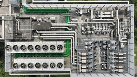 Top-down aerial view of an industrial rooftop with large HVAC systems, ventilation pipes, and cooling units. The photo shows intricate plumbing and green pipelines across a commercial building. - Powered by Shutterstock - Get 15% off with code: PIKWIZARD15