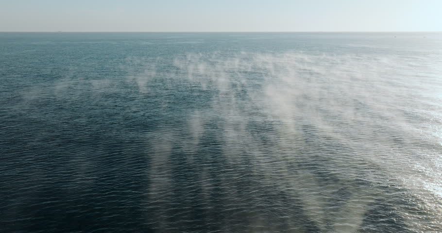 Sunrise over open sea with sun casting golden path of light across rippling water.Aerial gentle waves and soft sky create breathtaking, peaceful morning atmosphere scenic ocean view. Travel, relax