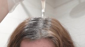 Coloring of gray hair.A woman applies hair dye to gray roots using a special applicator. The process of home coloring helps to return a rich color and hide gray hair. - Powered by Shutterstock - Get 15% off with code: PIKWIZARD15