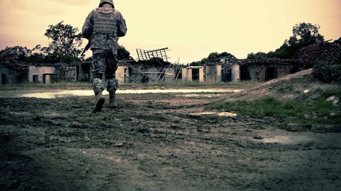 Graded shot of army soldier walking through ruins