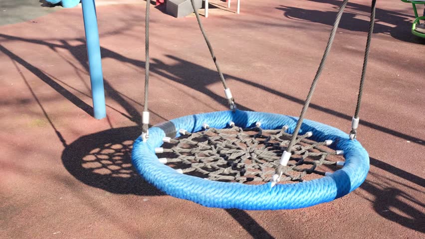 blue hanging round swing made of braided rope with a wicker seat in a city playground in a residential area. Children