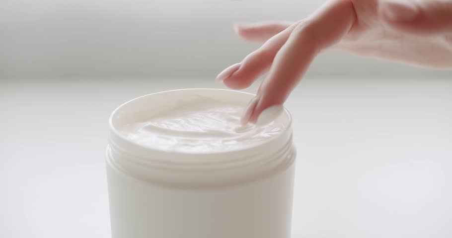 Woman hands takes lotion bottle applying moisturizing cream on hands. Bottles with cosmetic products and sponges for skincare massage. Skin care, hygiene and healthy life concept. Close up.