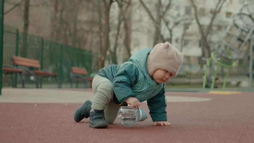 Baby cautiously takes first steps in a colorful playground, exploring various toys and enjoying time outdoors. The joy of childhood comes alive in this playful moment.