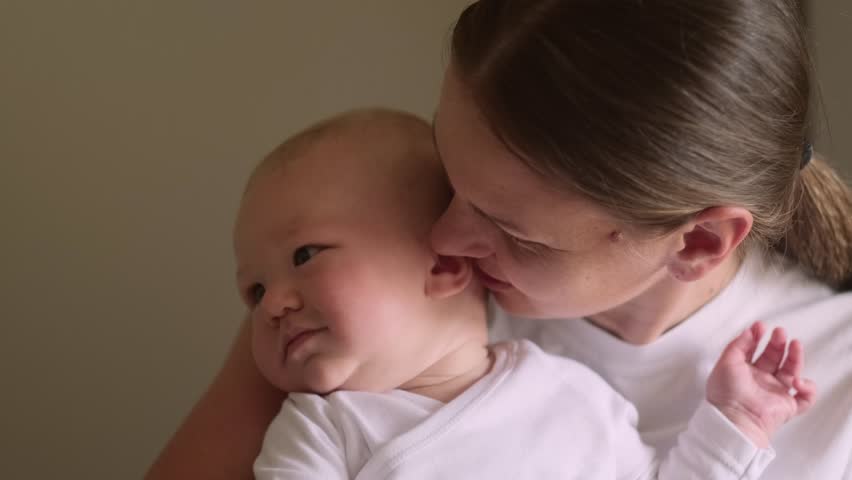 mother and baby share joyful moment as they smile at each other, baby is held securely in the mother arms, looking at her with delight, family love, bonding, parenting, childhood happines