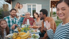 Group of people sitting together at table outdoors. Family gathering in village. Visiting parents. Looking at camera while waving. Celebrating something important. Enjoying tasty meals. - Powered by Shutterstock - Get 15% off with code: PIKWIZARD15