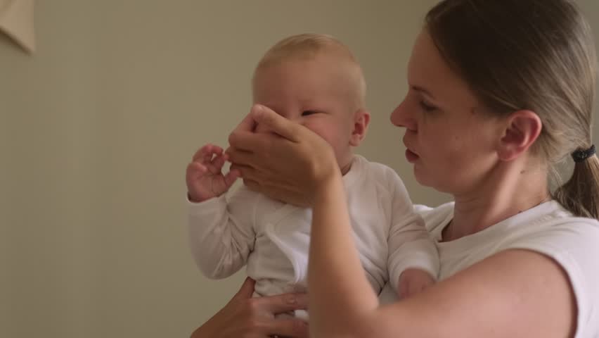 mother and baby share joyful moment as they smile at each other, baby is held securely in the mother arms, looking at her with delight, family love, bonding, parenting, childhood happines