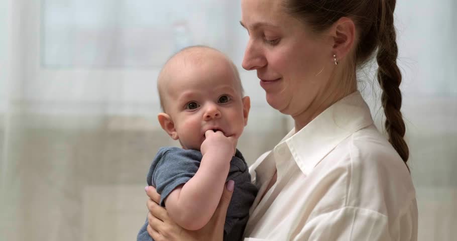 mother and baby share joyful moment as they smile at each other, baby is held securely in the mother arms, looking at her with delight, family love, bonding, parenting, childhood happines