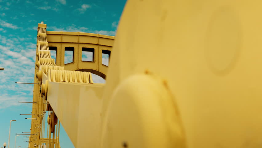 A shallow DOF dollying establishing shot of the yellow 6th Street Roberto Clemente Bridge over the Allegheny River in downtown Pittsburgh, PA. Right to left movement.  	