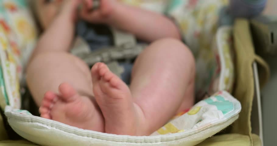baby legs close up, baby lies in baby seat with tiny feet raised in the air, child time, highlighting early sensory and motor development, home life, childhood growth
