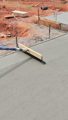 Concrete is being leveled with broom trowel at construction site with showcasing building process