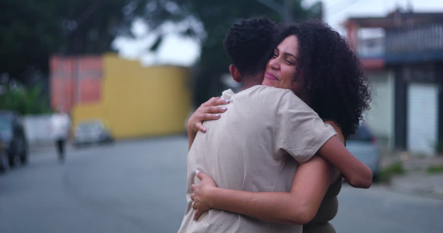Mother hugging her teenage son tightly with a bright smile, sharing a heartfelt moment of love and connection in a serene outdoor setting