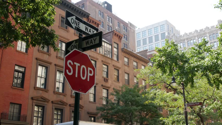New York City oneway crossroad, Stuyvesant street intersection one way arrow. Manhattan Midtown residential building architecture, United States real estate. Red brick house wall, red stop road sign.