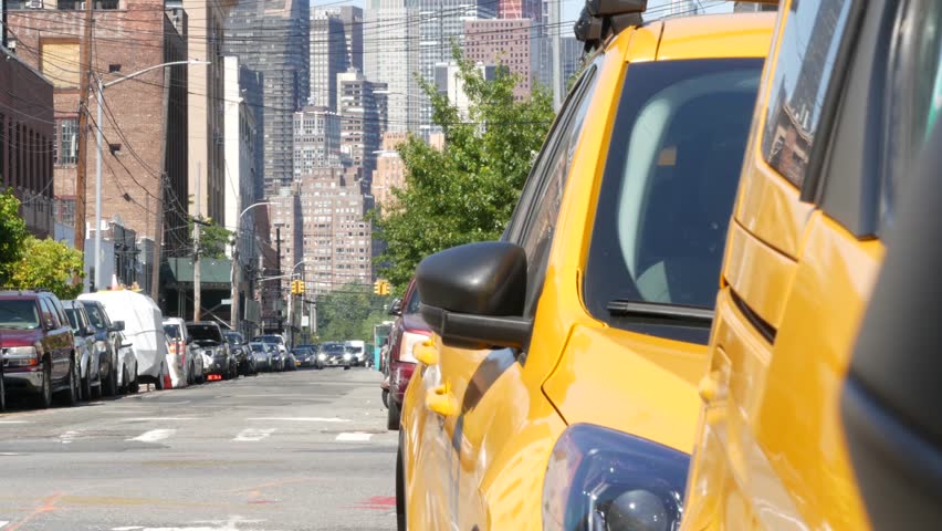 New York City. Row of yellow Taxi cars on street, Queens. Many taxi cabs on avenue, Long Island, LIC. Medallion taxicab and Manhattan Midtown urban skyline cityscape. High-rise building architecture.
