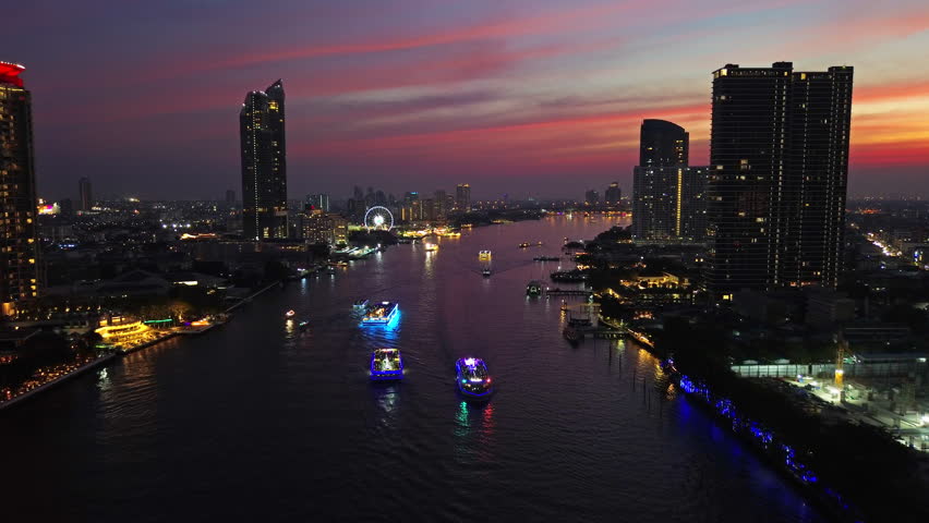 Aerial view of illuminated skyscrapers in Bangkok city and Chao Phraya River in night time, 4k
