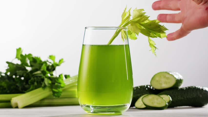 Fresh Green detox juice with cucumber, celery, apple and ginger and mint in glasses and jars. Pouring Vegan juice detox concept.