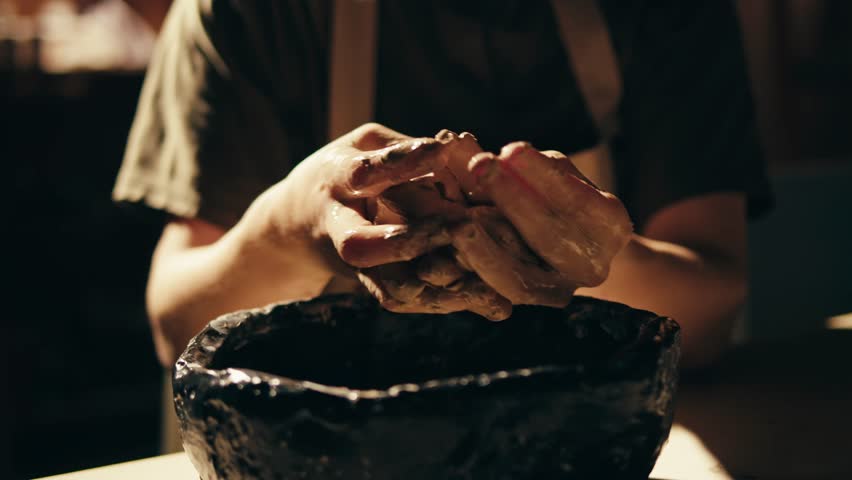Woman potter works with clay on master class in studio. Working process in ceramic workshop. Potter making vase on pottery wheel. Handmade concept. 