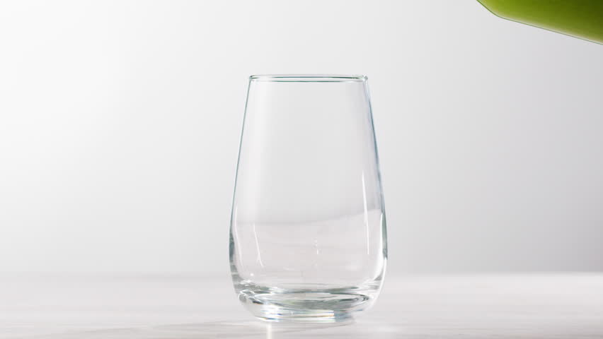 Fresh Green detox juice with cucumber, celery, apple and ginger and mint in glasses and jars. Pouring Vegan juice detox concept.