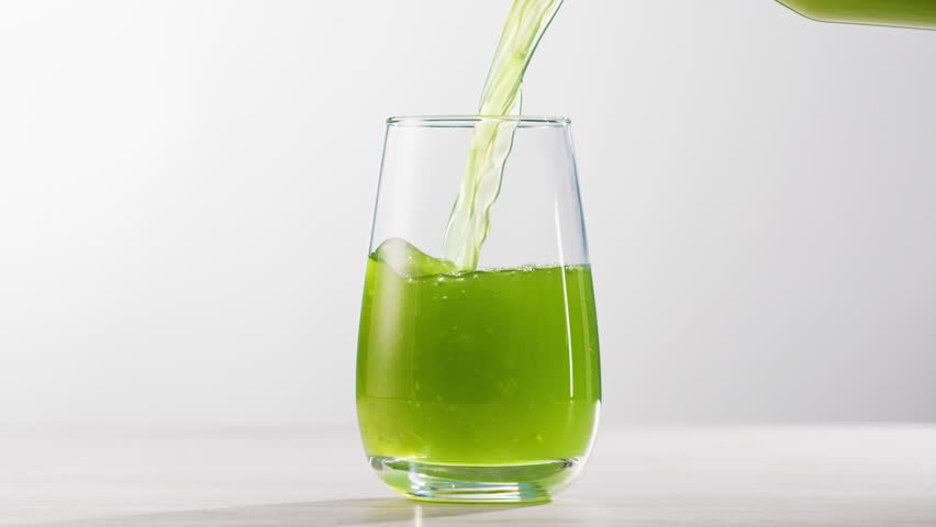 Fresh Green detox juice with cucumber, celery, apple and ginger and mint in glasses and jars. Pouring Vegan juice detox concept.