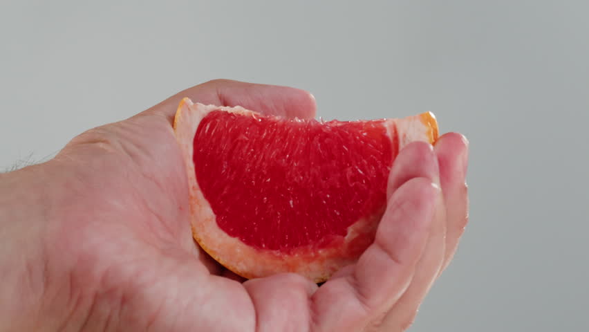Woman pouring grapefruit juice from juicer into glass on colorful background, citrus vitamic c healthy fresh juice in cafe, morning breakfast drink.