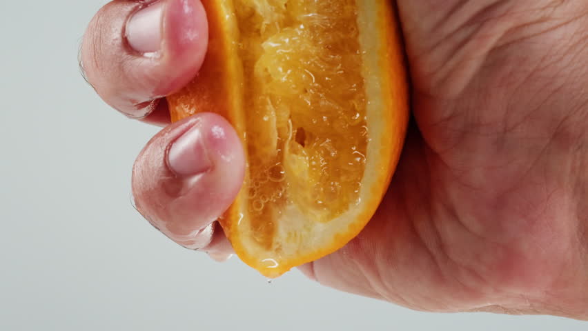 Woman pouring orange grapefruit juice from juicer into glass on colorful background, citrus vitamic c healthy fresh juice in cafe, morning breakfast drink.