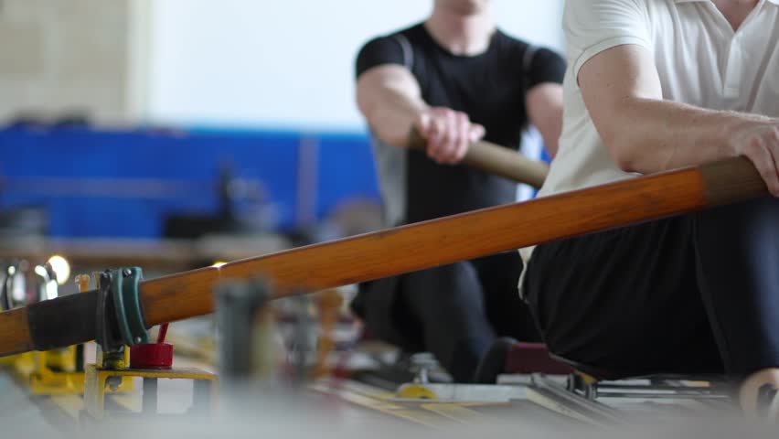 Water sports rowing simulator. Closeup rowing team hands work with paddles, preparing for competitions. Arms make circular motions developing flexibility stability, muscle memory and concentration