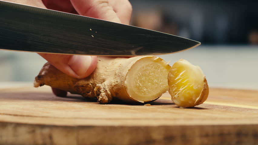 Ginger root and sliced on old plank with nature background. Close-up, food texture, tea lemonade ingredient in bar.