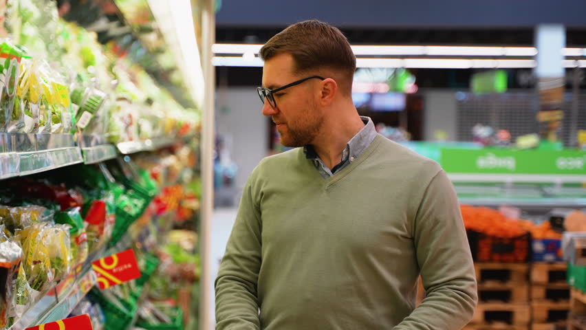Man browsing fresh salad options in grocery store aisle