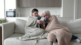 Sick wife and husband battling flu, gloomy couple bundled in blankets sipping hot tea on sofa. Virus infection, cold symptoms, nasal congestion, exhaustion, fatigue recovery at home, immune support - Powered by Shutterstock - Get 15% off with code: PIKWIZARD15