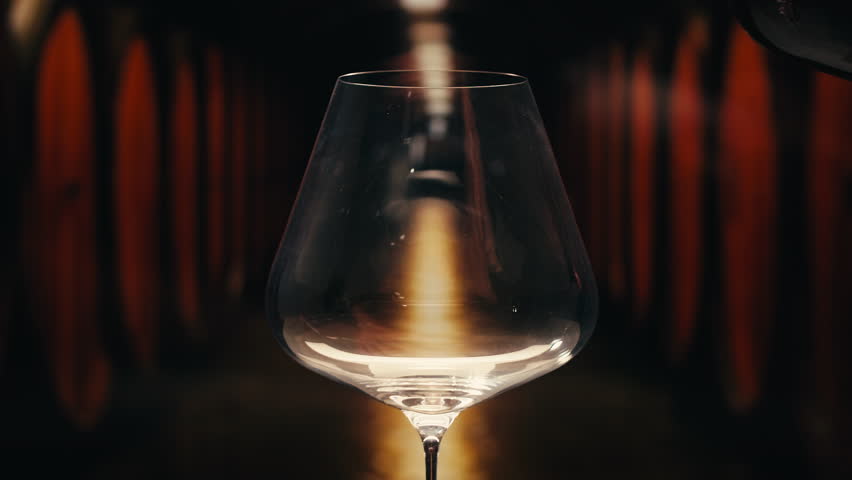 Orange or red wine bottle and glass against a sunset in a peaceful vineyard, pouring of ecological natural wine. 