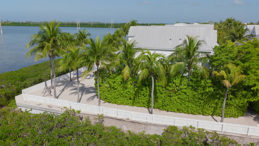 See the stunning aerial view of Sunset Key in Key West, Florida, with lush greenery, a welcoming waterfront, beautiful architecture, and a vibrant blue skya paradise for nature lovers