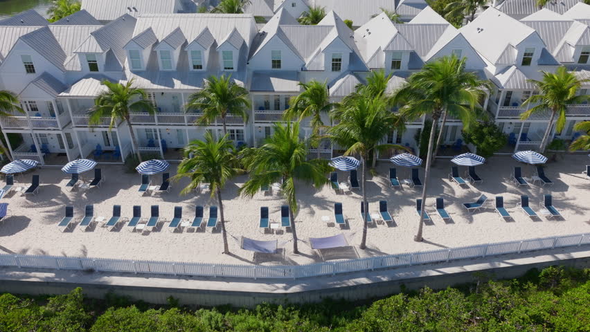 This stunning aerial view showcases Sunset Key in Key West, Florida, emphasizing its luxurious accommodations and inviting lounge areas amid lush palm trees, a true paradise for relaxation