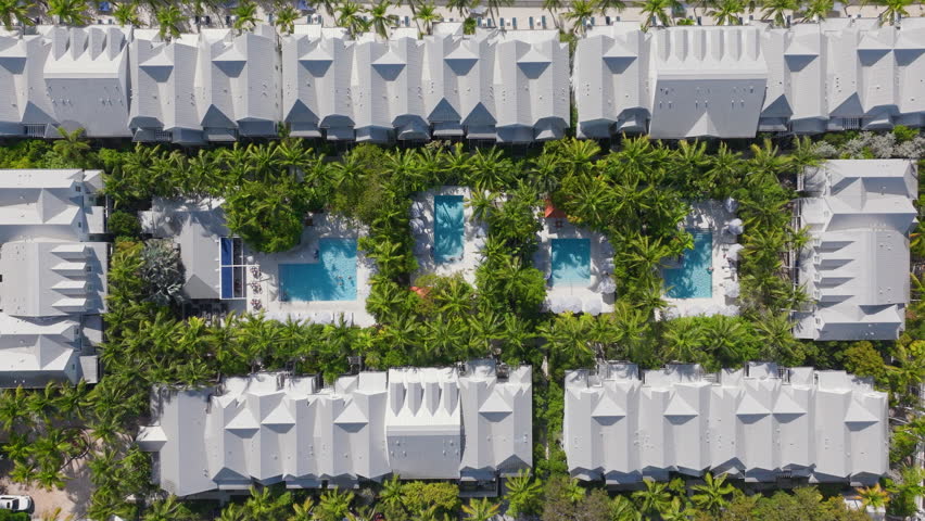 Experience the stunning aerial view of Sunset Key in Key West, Florida, featuring beautiful landscaping and refreshing pools among vibrant greenery, perfect for relaxation